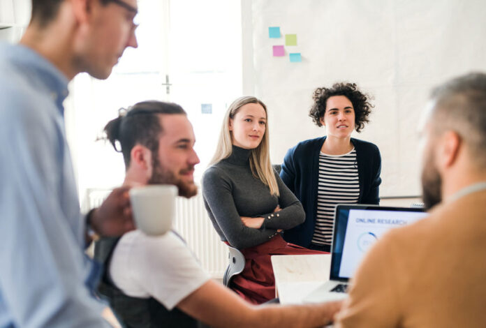 Group of young businesspeople with laptop working together in a modern office.