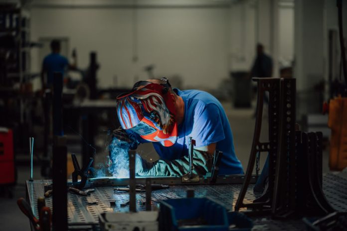 Professional Heavy Industry Welder Working Inside factory, Wears Helmet and Starts Welding. Selective Focus